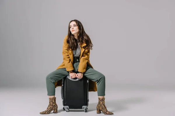 Modisch Elegantes Mädchen Beigen Mantel Sitzt Auf Reisetasche Auf Grau — Stockfoto