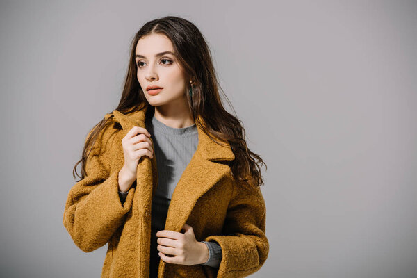 beautiful elegant woman posing in beige coat, isolated on grey