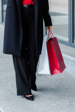 İş kadınının yürürken ve alışveriş torbaları tutarken çekilmiş görüntüsü 