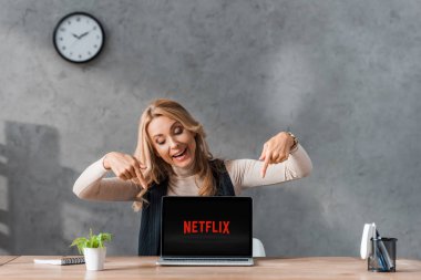 Kyiv, Ukrayna - 16 Ağustos 2019: gülümseyen iş kadını dizüstü bilgisayarını netflix logosuyla işaret ediyor 