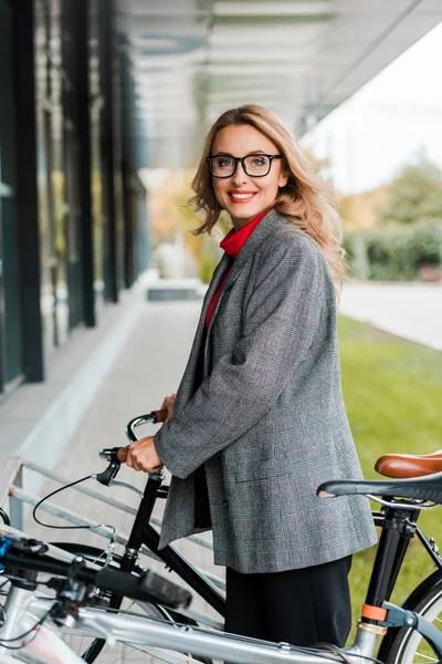 Atractiva Mujer Negocios Abrigo Gafas Sonriendo Sosteniendo Bicicleta — Foto de Stock