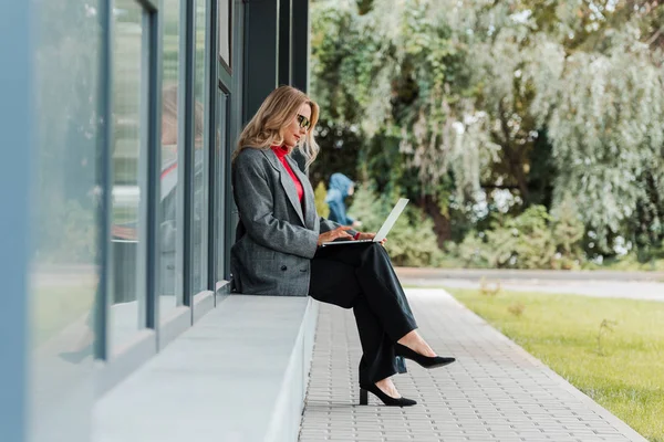 Zijaanzicht Van Aantrekkelijke Zakenvrouw Jas Met Behulp Van Laptop — Stockfoto