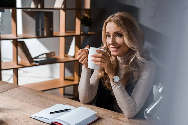 Attraktiv Och Leende Affärskvinna Sitter Vid Bordet Och Håller Kopp — Stockfoto