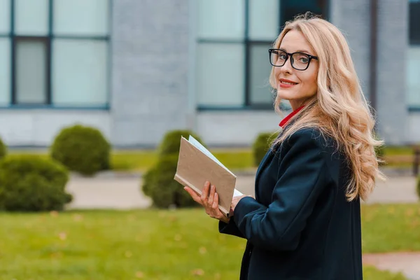 Attractive Smiling Businesswoman Black Coat Holding Book — Stock Photo, Image