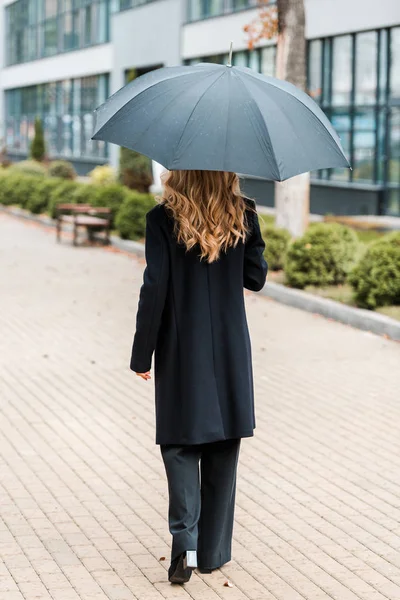 Rückenansicht Einer Geschäftsfrau Schwarzen Mantel Die Mit Regenschirm Läuft — Stockfoto
