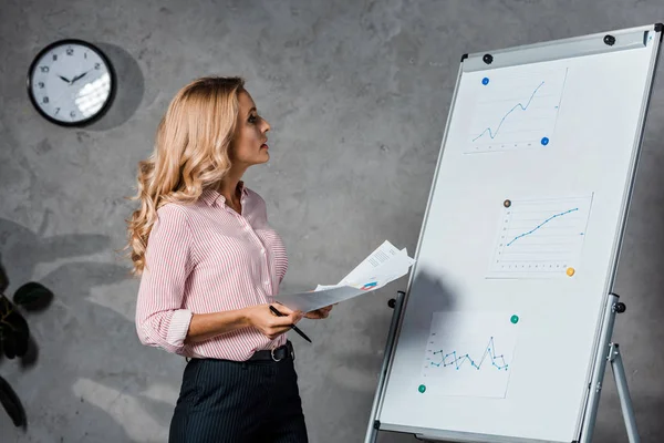 Attractive Blonde Businesswoman Shirt Holding Papers Looking White Board Office — Stock Photo, Image