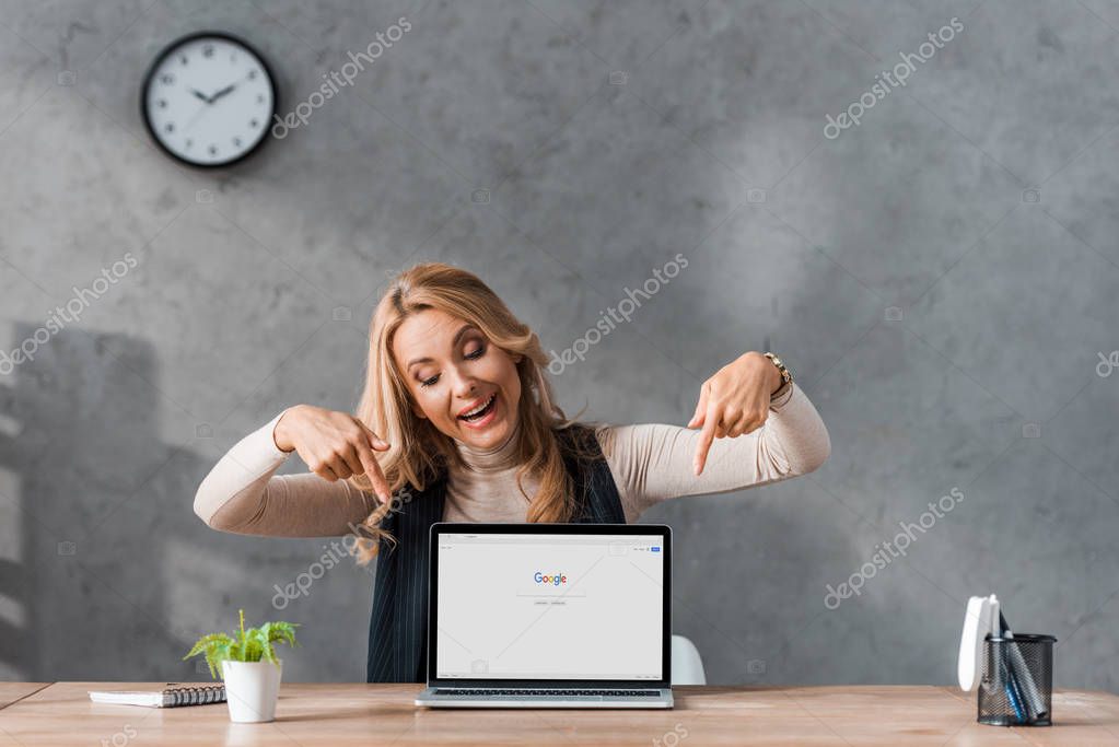 KYIV, UKRAINE - AUGUST 16, 2019: smiling businesswoman pointing with fingers at laptop with google logo