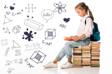 cheerful schoolkid sitting on books and reading near letters and mathematical formulas  on white 