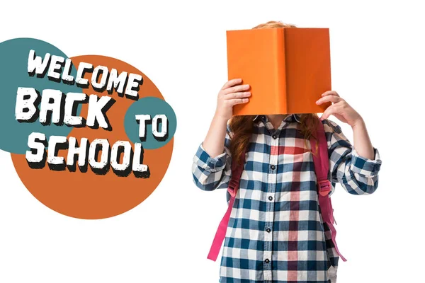 pupil covering face with orange book near welcome back to school letters on white