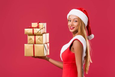 Noel Baba şapkası ve Noel elbisesi giymiş neşeli Afro-Amerikalı kız elinde kırmızı kutular tutuyor.