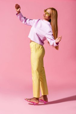 Pembe arka planda duran şık Afro-Amerikan kadın, moda bebeği konsepti