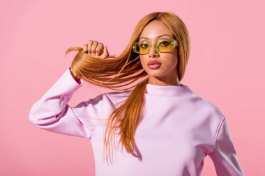 şık, çekici Afrikalı Amerikalı kadın saçına dokunuyor pembe, moda bebeği konseptinde izole edilmiş.