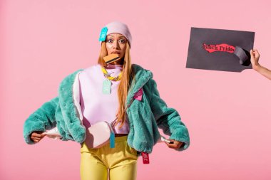 Siyah Cuma yazılı yırtık kağıt tutan bir kadının, Afro-Amerikan bir kadının, pembe, moda bebeği kavramında izole edilmiş boş ceplerini göstermesi.