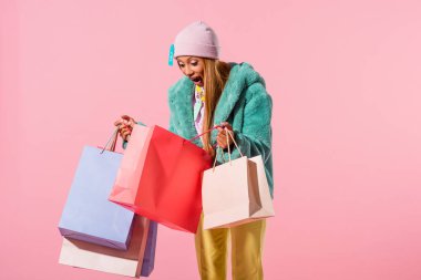 Komik, modaya uygun Afrikalı Amerikalı kadın pembe arka planda alışveriş çantasına bakıyor, oyuncak bebek konsepti.