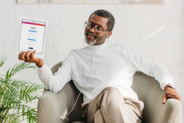 Kyiv, Ukrayna - 2 Ekim 2019: Kulaklıklı Afro-Amerikan adam ekranda Instagram uygulamalı dijital tableti gösteriyor.