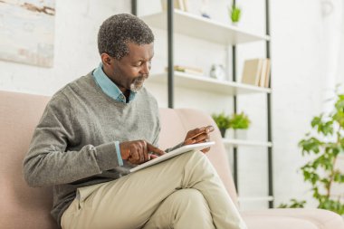 Dikkat Afro-Amerikan adam dijital tablet kullanırken kredi kartı tutuyor.