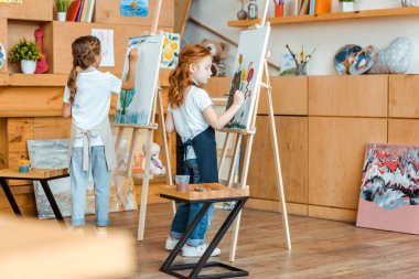 Sanat okulunda duran ve resim yapan sevimli çocukların seçici odağı 