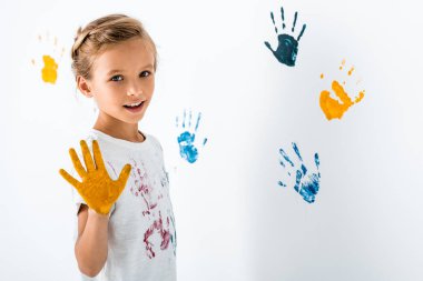 Sarı boyalı mutlu çocuk, beyaz ellerin yanında. 