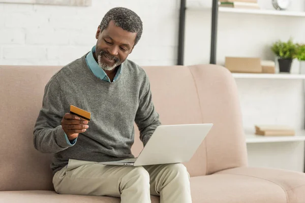Ανώτερος Αφροαμερικάνος Κάθεται Καναπέ Φορητό Υπολογιστή Και Κρατώντας Πιστωτική Κάρτα — Φωτογραφία Αρχείου