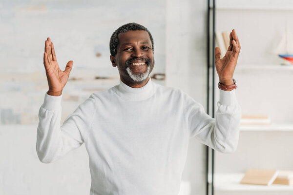  happy african american man showing wow gesture and smiling at camera