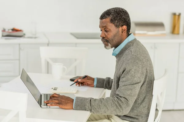 Серйозний Афроамериканський Чоловік Використовує Ноутбук Під Час Розрахунку Витрат — стокове фото