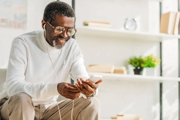 Alegre Afroamericano Hombre Usando Smartphone Mientras Escucha Música Auriculares — Foto de Stock