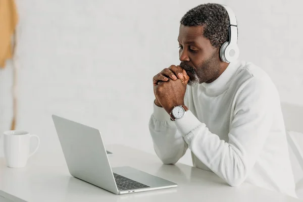 Serious African American Man Listening Music Headphones While Sitting Laptop — ストック写真