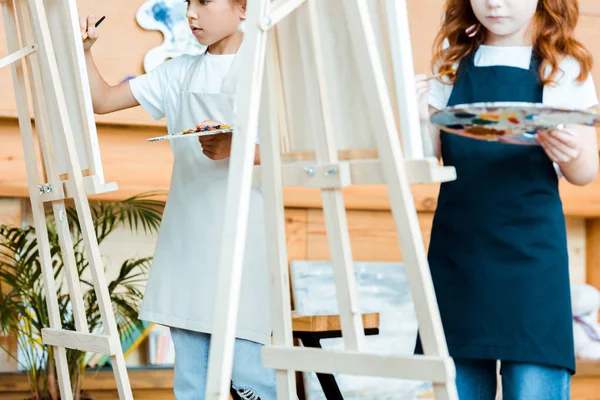 Vista Recortada Los Niños Delantales Pie Cerca Caballetes Con Paleta — Foto de Stock