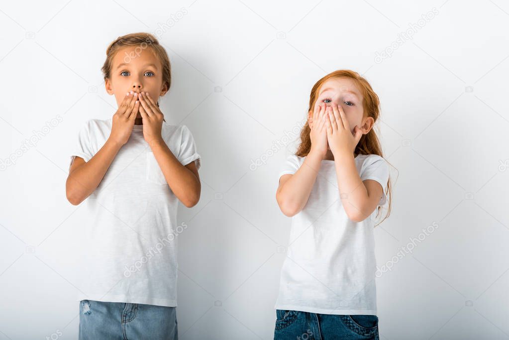 cute kids standing and covering faces on white 