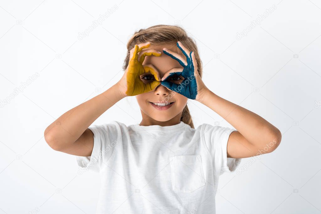 cheerful kid showing ok sign while covering face isolated on white 