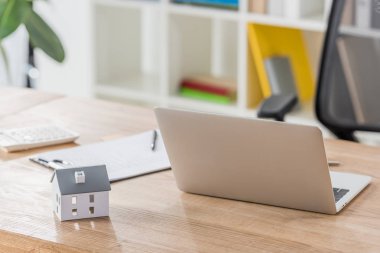 Ofisteki ahşap masada dizüstü bilgisayar, ev modeli, dosya ve hesap makinesi