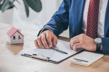 İş yerindeki iş adamının pano, ev modeli ve hesap makinesinin yanındaki kısmi görünümü 