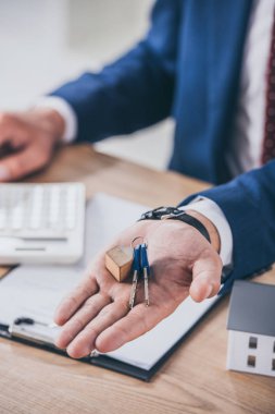 İş yerindeki iş adamının ev modeli, pano ve hesap makinesinin yanındaki anahtarları gösteren kısmi görünümü