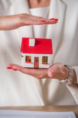 Ev modelini el ele tutuşup kaplayan iş kadınının kısmi görüntüsü 