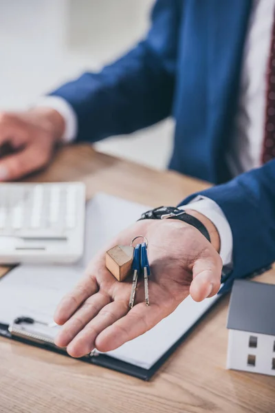 İş yerindeki iş adamının ev modeli, pano ve hesap makinesinin yanındaki anahtarları gösteren kısmi görünümü