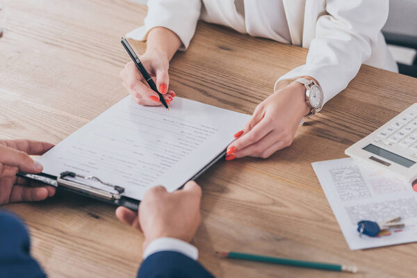 cropped view of businessman holding clipboard and woman signing contract