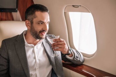 Yakışıklı iş adamı özel jette martini bardağıyla içki tutuyor. 
