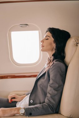 Özel jette müzik dinleyen çekici iş kadınının yan görüntüsü 