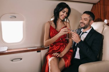 Özel jetlerinde martini bardakları tutan mutlu çift. 
