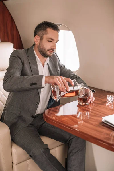 Knappe Zakenman Gieten Whisky Glas Terwijl Zitten Prive Jet — Stockfoto