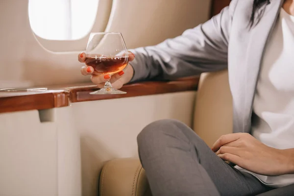 Beskärd Utsikt Över Affärskvinna Håller Glas Med Konjak Privat Jet — Stockfoto