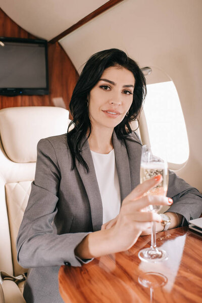 привлекательная деловая женщина с бокалом шампанского в частном самолете
 