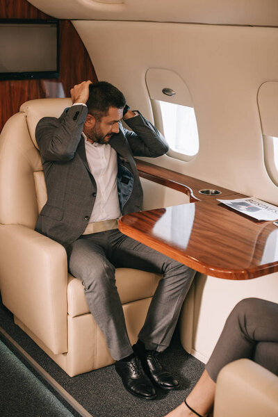 обрезанный вид деловой женщины, сидящей с бородатым бизнесменом в самолете
 
