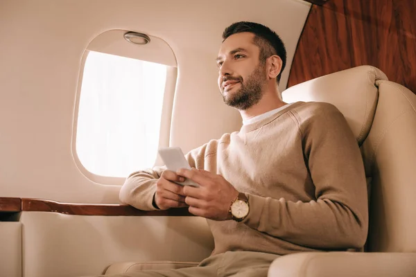 Guapo Barbudo Hombre Sosteniendo Teléfono Inteligente Mientras Está Sentado Jet —  Fotos de Stock