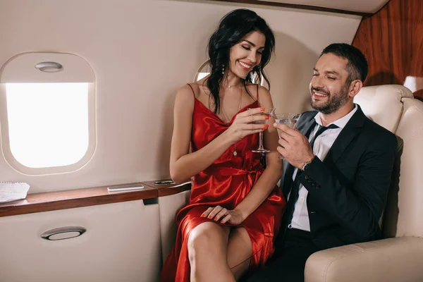 Özel jetlerinde martini bardakları tutan mutlu çift. 