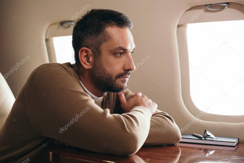 handsome bearded man sitting in first class of private jet 