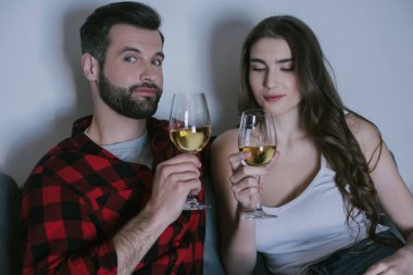 Neşeli adam ve çekici kız ellerinde beyaz şarap kadehleriyle