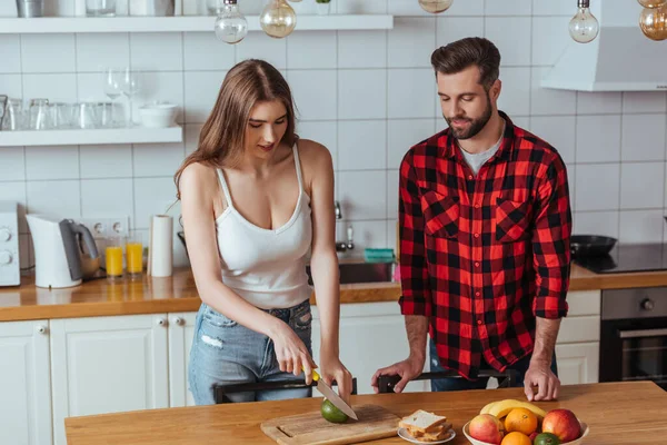 Vacker Ung Kvinna Skär Färsk Avokado Nära Stilig Pojkvän — Stockfoto