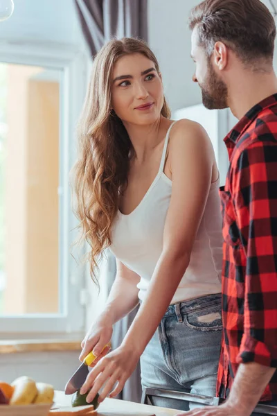 Atractiva Chica Joven Mirando Novio Mientras Corte Aguacate Fresco — Foto de Stock