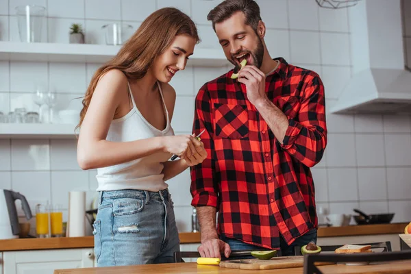 Homem Bonito Feliz Degustação Fatia Abacate Fresco Perto Bela Namorada — Fotografia de Stock